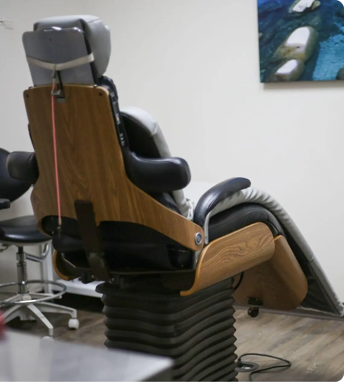 Comfortable dental treatment chair with wood armrests and black leather upholstery in modern office.