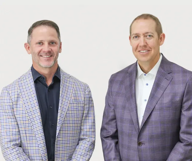 Two dentists smiling in professional blazers at a Lubbock dental practice.
