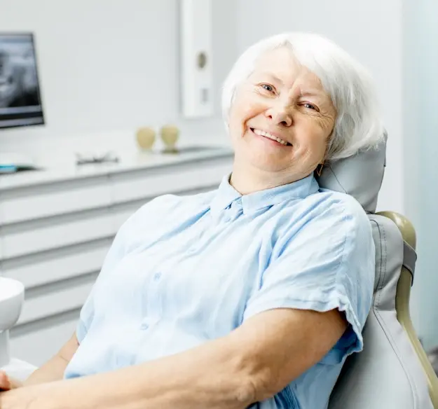 Senior woman smiling in dental chair after successful root canal treatment.