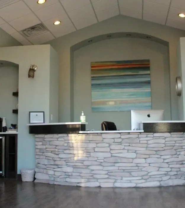 Modern dental office reception area with curved stone desk and colorful artwork at Maupin Steffensen Endodontics in Lubbock.